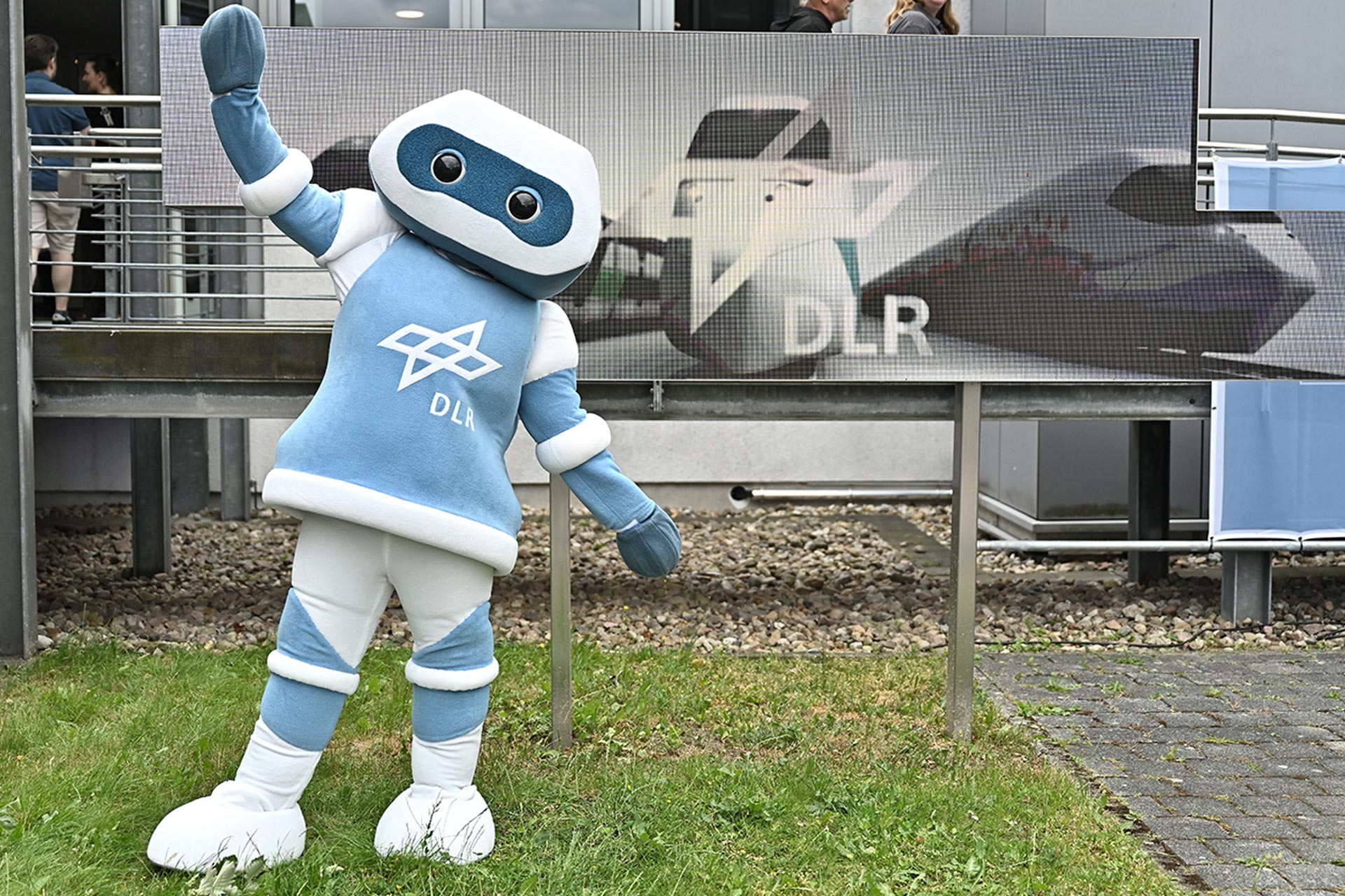 Arti, das sympathische DLR-Maskottchen, empfängt die Gäste am Tag der offenen Tür des Deutschen Zentrums für Luft- und Raumfahrt zur 25. Langen Nacht der Wissenschaften in Berlin. Maskottchen Arti vom Deutschen Zentrum für Luft- und Raumfahrt (DLR) begrüßt Besucherinnen und Besucher der Langen Nacht der Wissenschaften 2025 in Berlin vor einem DLR-Informationsbanner.